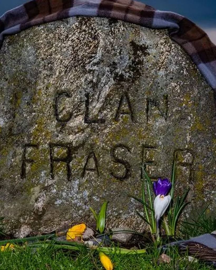 A memorial stone carved Clan Fraser, draped in tartan, on Culloden battlefield